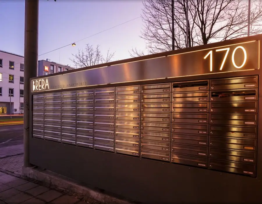 Beleuchtete Briefkastenanlage vor Wohngebäude bei Dämmerung mit Hausnummer 170.